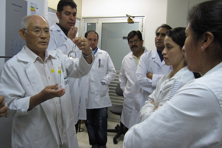2011年，水俣市国际汞研究所所长赤木洋胜（左）向来自中南美的研究者传授汞分析法。（赤木洋胜  提供）